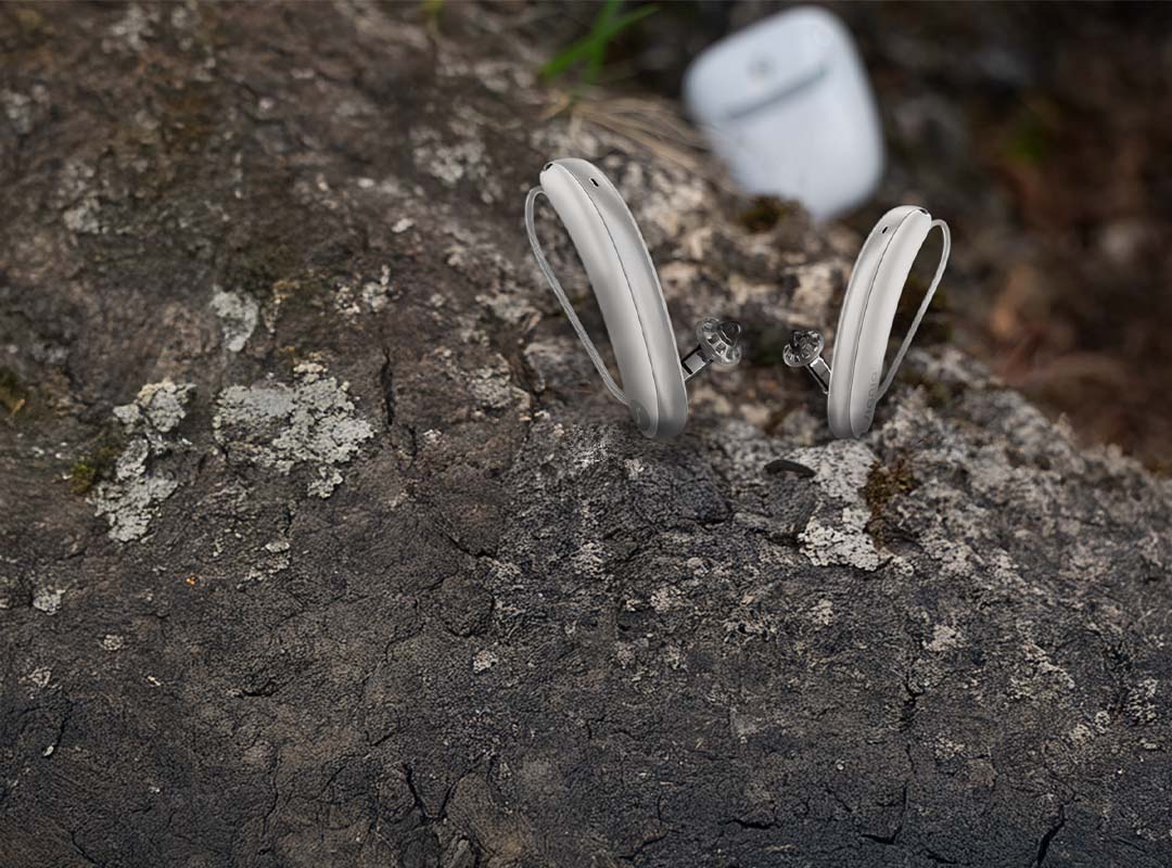Weiße Hörgeräte Signia Styletto IX mit Ladestation auf einem Felsen