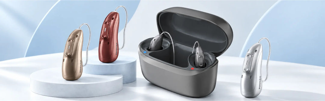 Drei Phonak Audeo EON Sphere Hörgeräte und eine LAdestation mit Hörgeräten auf einem hellen Tisch